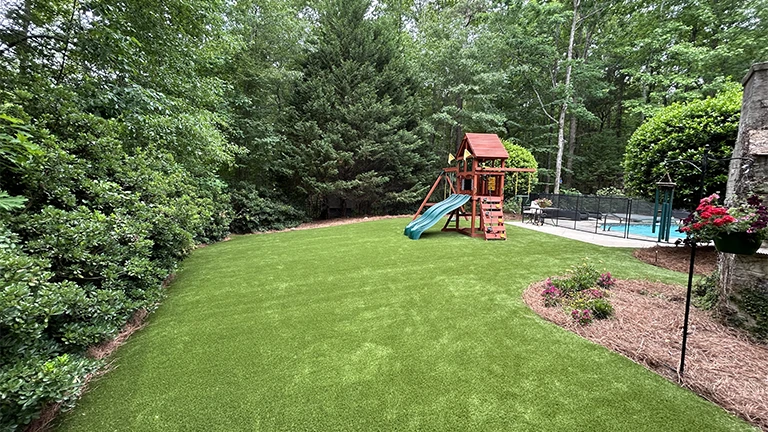 Eco-friendly synthetic turf installation in a Knoxville residential yard, offering a low maintenance and durable artificial lawn solution.